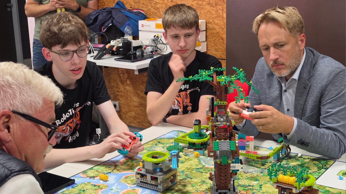 Bild: MdL Martin Stock (rechts) probiert gemeinsam mit den Sch�lerinnen und Sch�lern die selbst gebauten LEGO-Modelle aus und taucht in die Welt der Robotics ein.